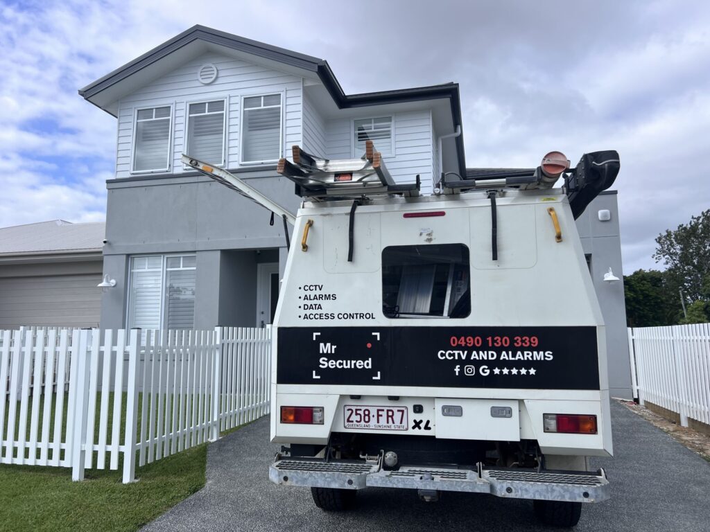 Mr Secured van at a white double-storey home with picket fence